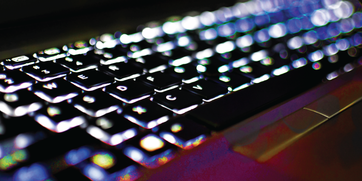 Close-up of a black keyboard, glowing from underneath, to symbolize a Business Email Compromise (BEC) cyberattack.